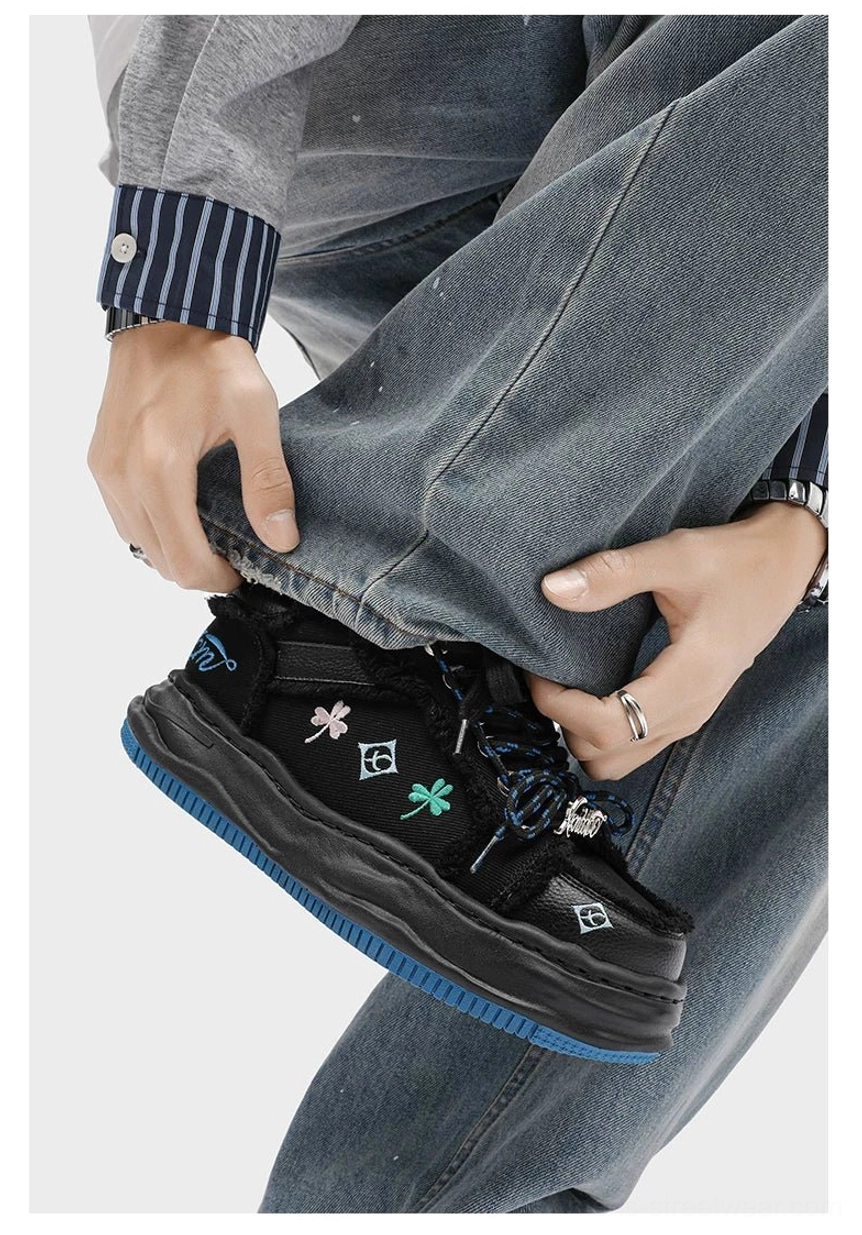 Black distressed embroidered platform sneaker worn with denim showing relaxed on-foot fit and layered streetwear details
