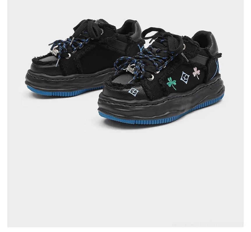 Black distressed embroidered platform sneaker pair with matching colorful embroidery and blue rubber platform midsoles