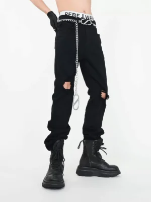 Three quarter side view of black distressed knee ripped straight leg jeans with silver metal chain detail and combat boots