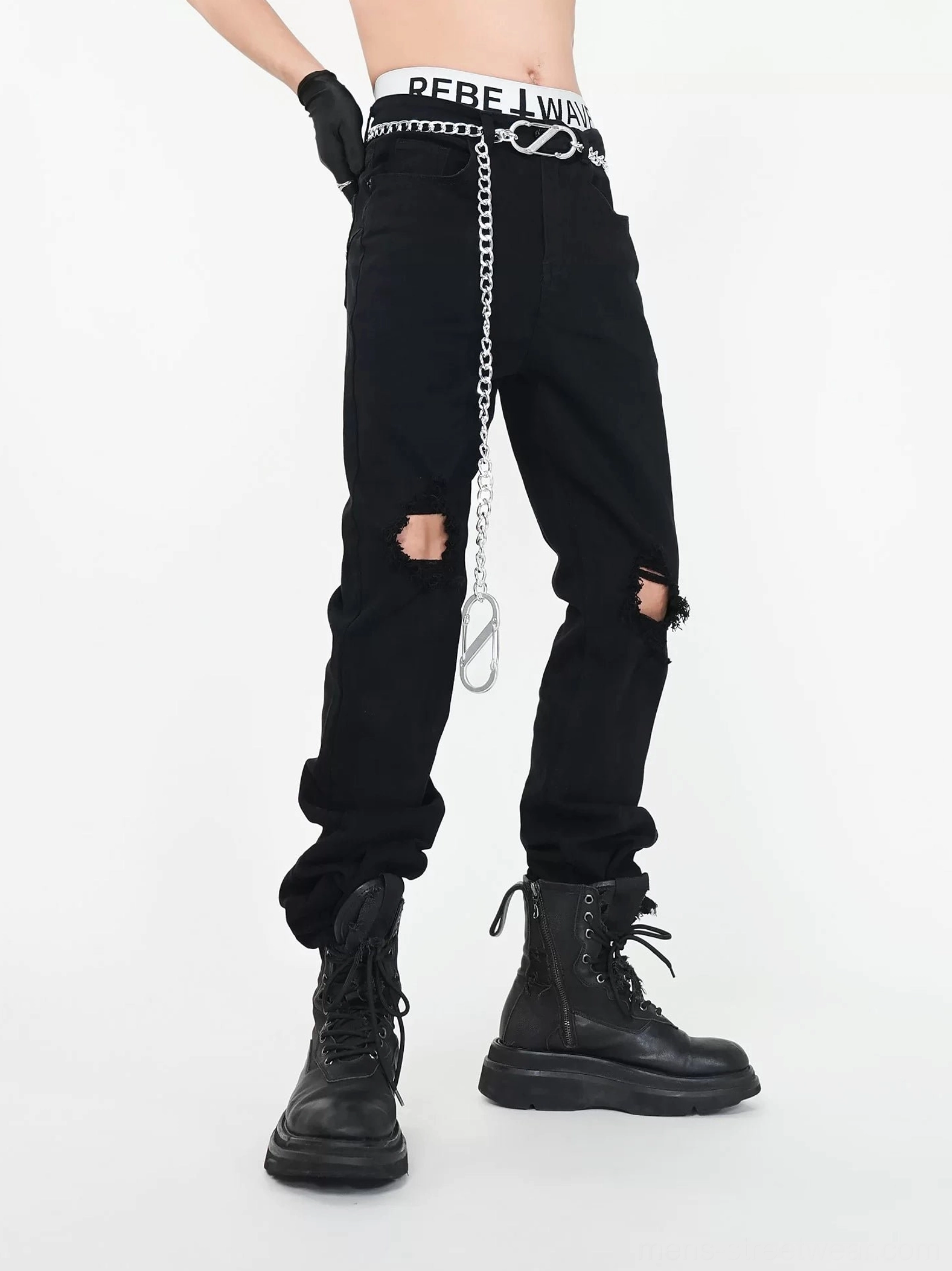 Three quarter side view of black distressed knee ripped straight leg jeans with silver metal chain detail and combat boots