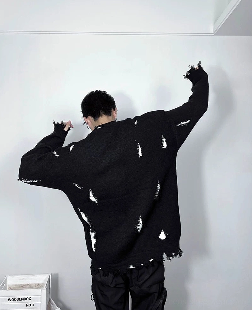 Back view of a black oversized distressed knit sweater showing scattered frayed details, unfinished hem, dropped shoulders, and clean graphic-free back