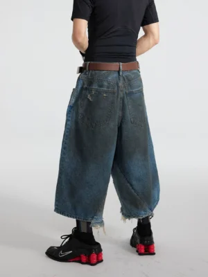 Rear full-body view of black distressed oil-washed cropped denim gaucho jeans showing dual back pockets, ultra-wide legs, and frayed raw hems