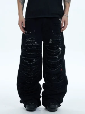 Low-angle front view of black distressed rhinestone wide-leg cargo jeans with ripped washed denim, side utility pockets, metal charms, and black work boots