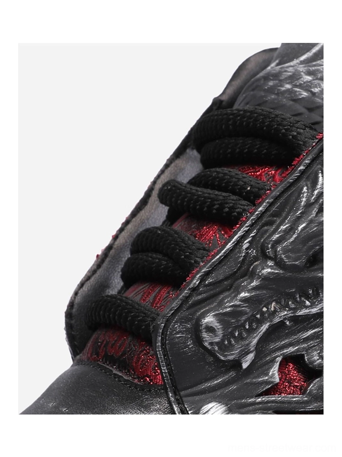 Close up of black dragon relief chunky platform sneaker showing textured dragon embossing black laces and red underlay