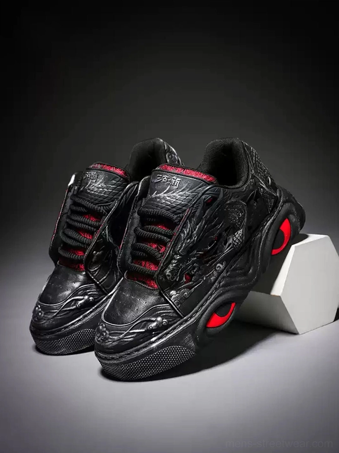 Pair of black dragon relief chunky platform sneakers with red lining and red outsole details three quarter product view