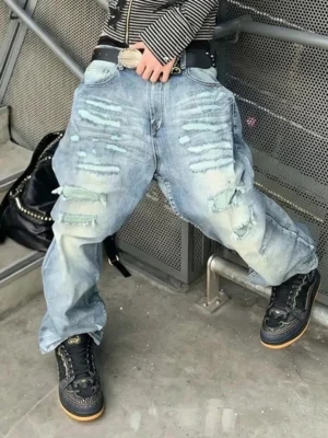 Black dragon scale streetwear sneakers styled with ripped light blue baggy jeans and a striped long sleeve top in an industrial setting