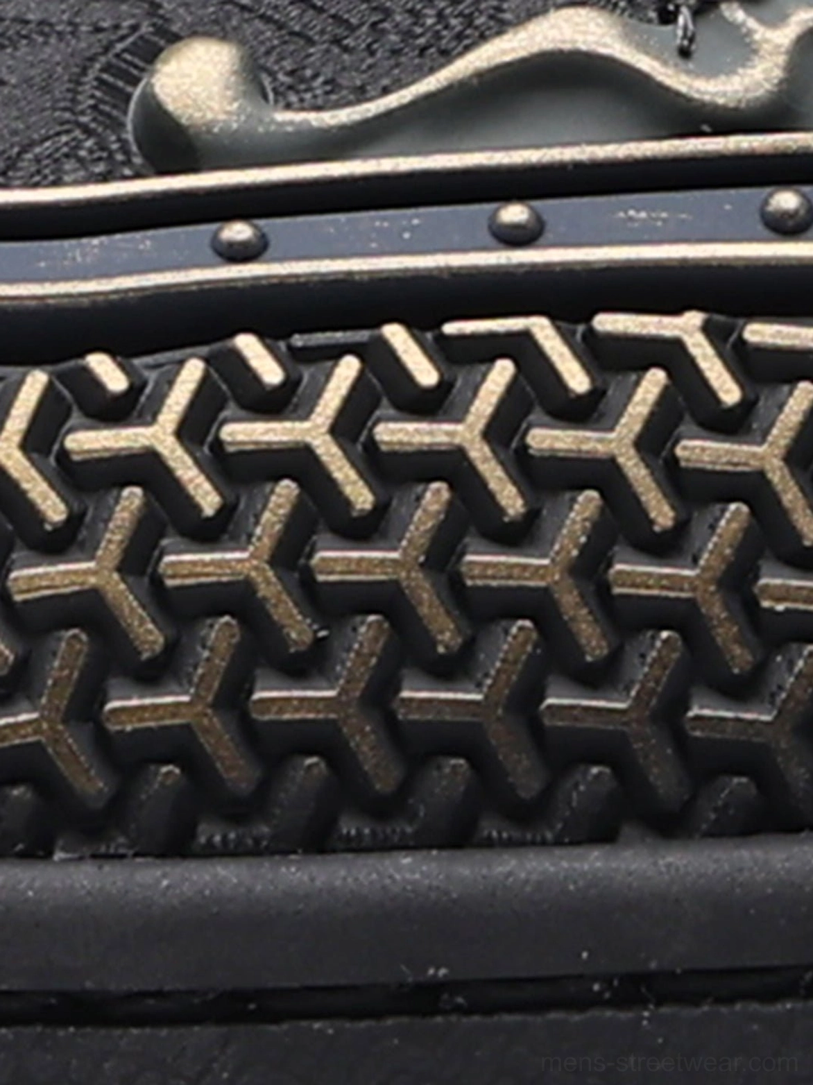 Close-up of black dragon sneaker perforated upper, geometric texture, bronze hardware, metal rivets, and patterned gum outsole