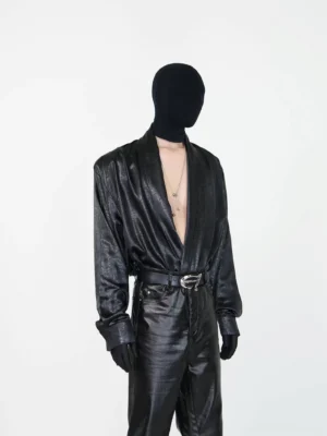Black draped faux leather deep V shirt styled with black flared pants in a front three-quarter avant-garde streetwear outfit