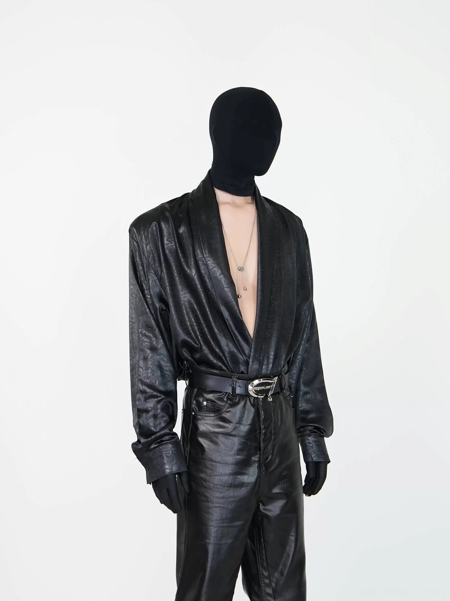 Black draped faux leather deep V shirt styled with black flared pants in a front three-quarter avant-garde streetwear outfit
