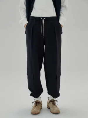 Black draping drawstring cargo casual pants front full-length view men's streetwear styling with white inner top and brown leather shoes