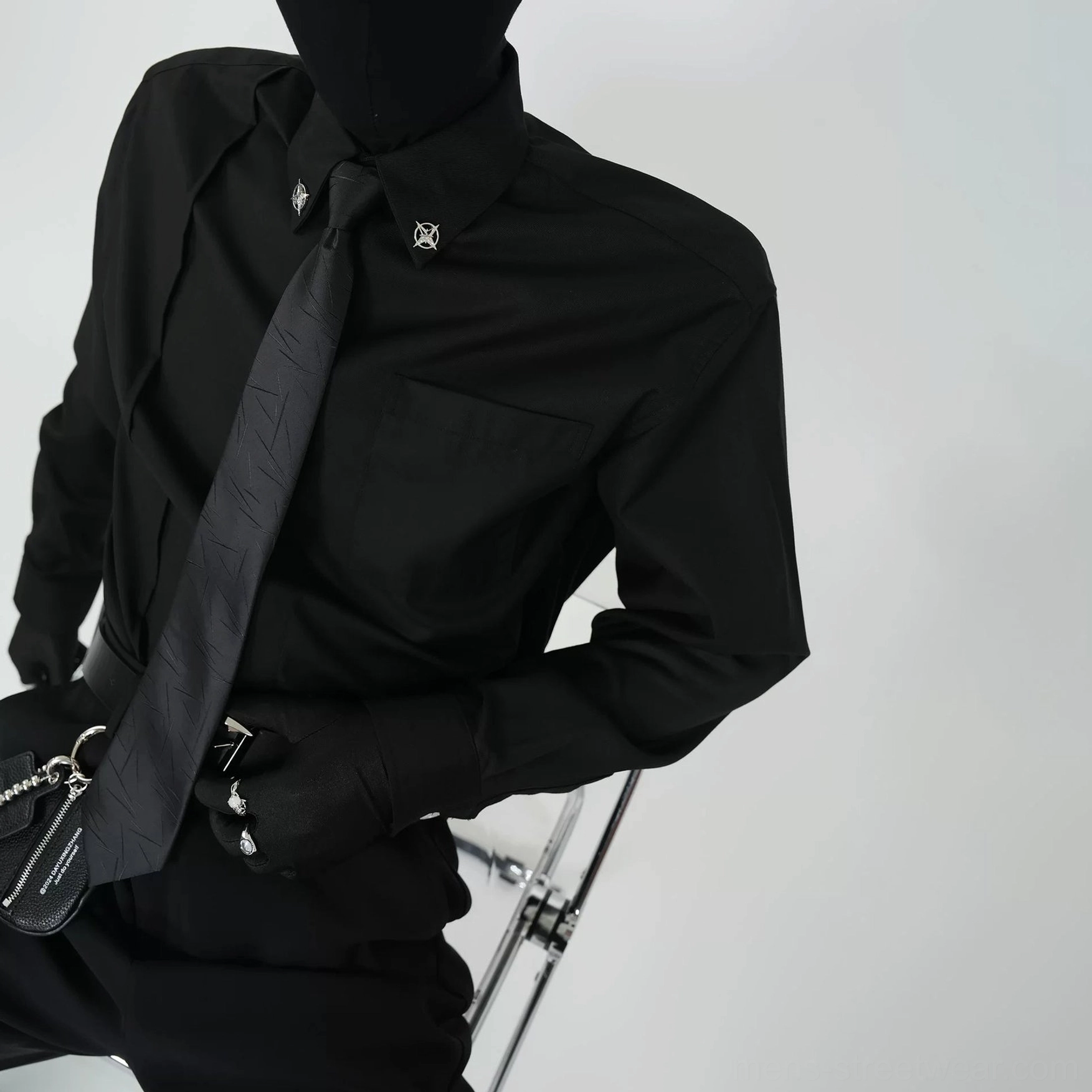 Black monochrome dress shirt with decorative silver collar pins and embossed black tie in an avant-garde formal streetwear close-up