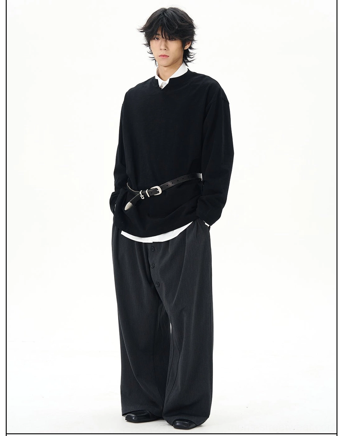 Side-front view of a black drop-shoulder oversized streetwear shirt styled with wide-leg trousers and a black leather waist belt