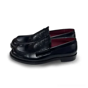 Black leather loafers shown in three-quarter view with embossed vamp detail, polished finish, neat stitching, and deep burgundy interior