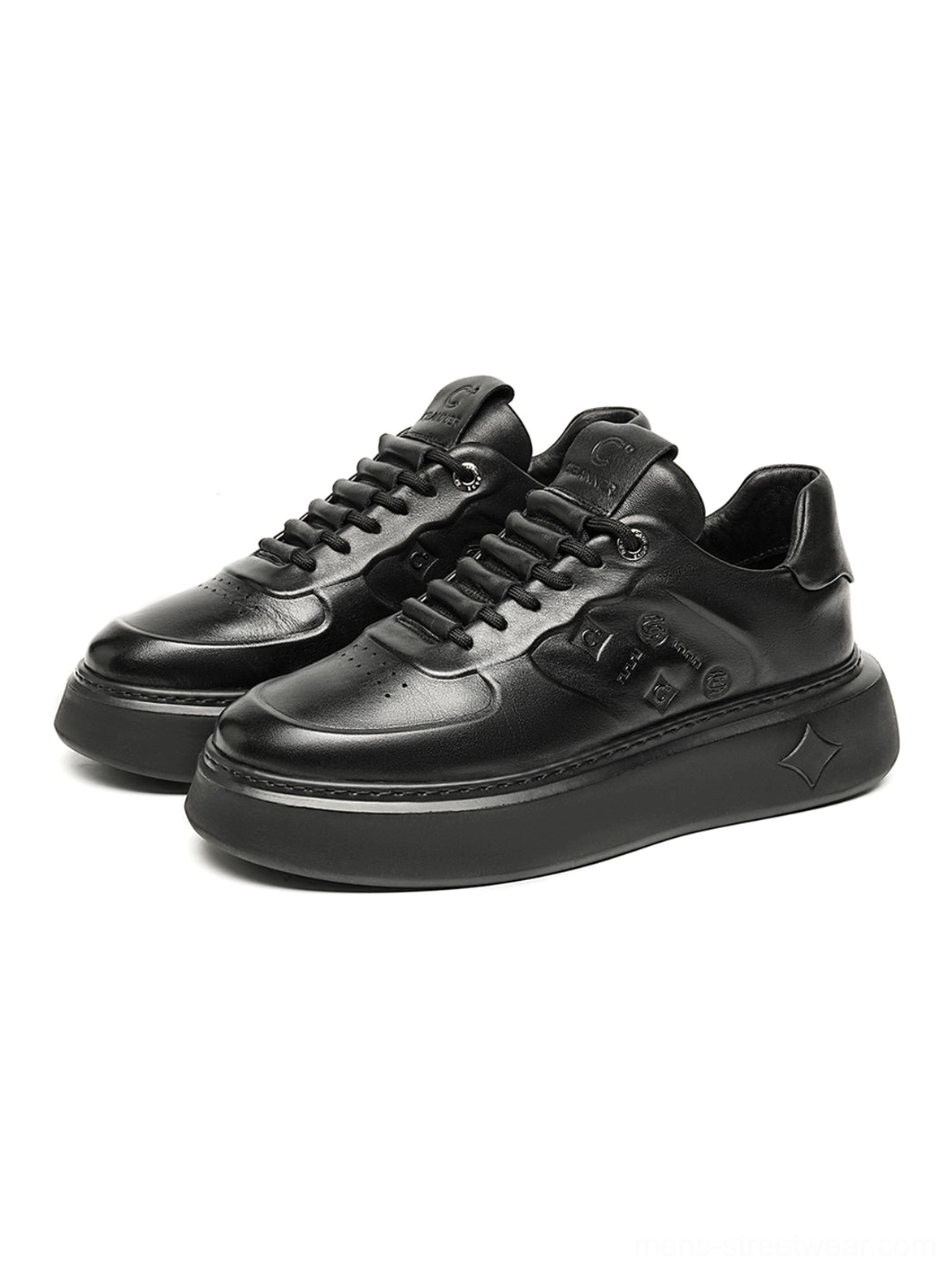 Pair of black embossed low-top platform sneakers arranged on a dark background showing the sleek monochrome silhouette