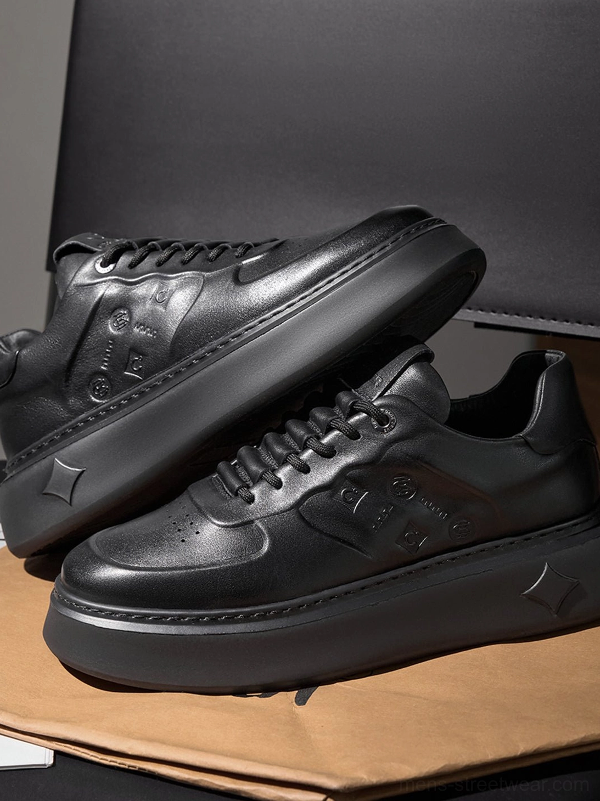 Black embossed platform sneakers shown from the side highlighting the thick chunky sole and all-black textured finish
