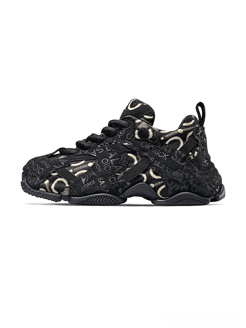 Black embroidered chunky dad sneakers with black suede overlays, gold-toned monogram jacquard panels, lace-up front, and layered rubber outsole