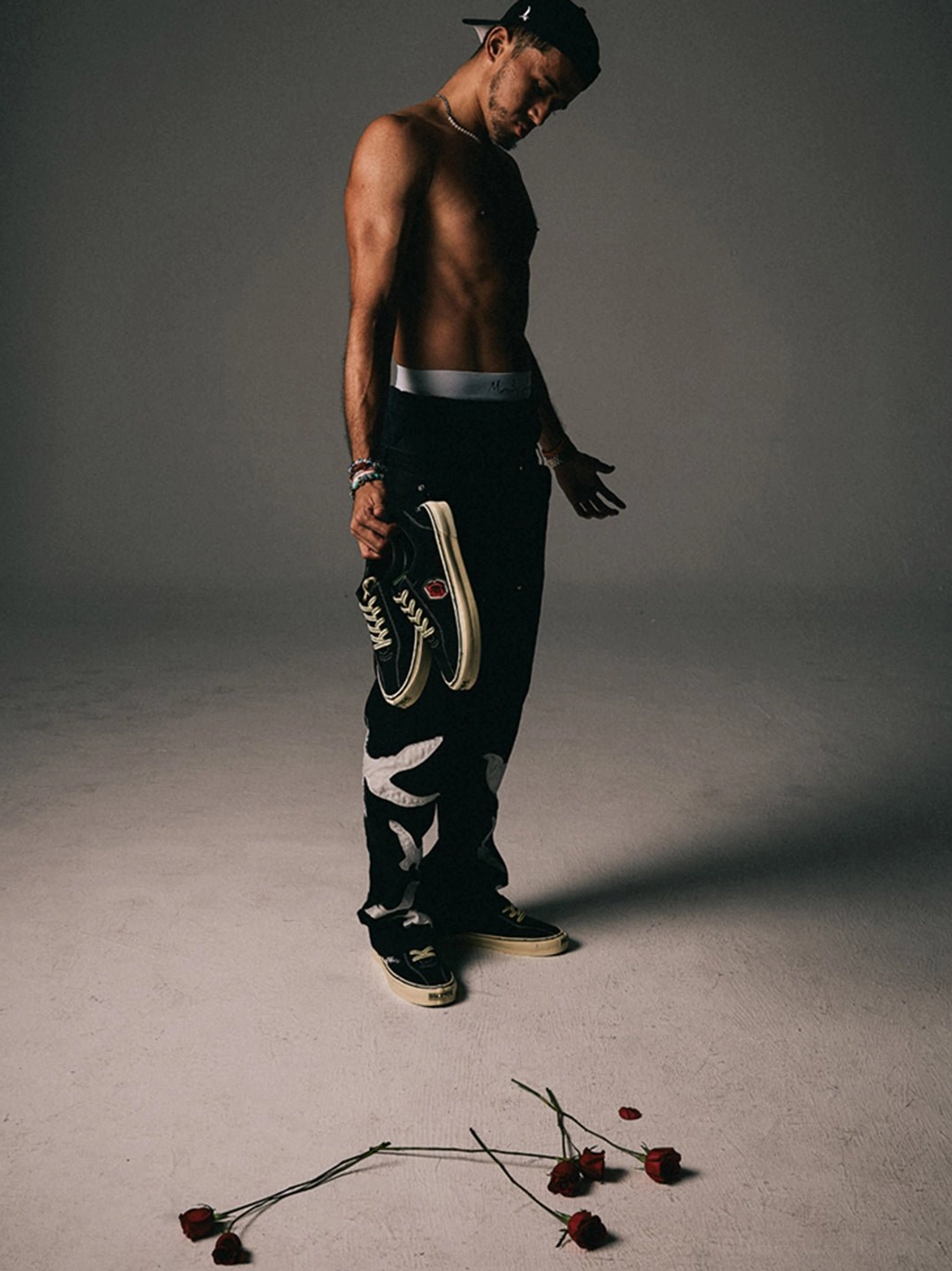 Side view of a male model wearing black embroidered low-top skate shoes with rose-inspired studio styling