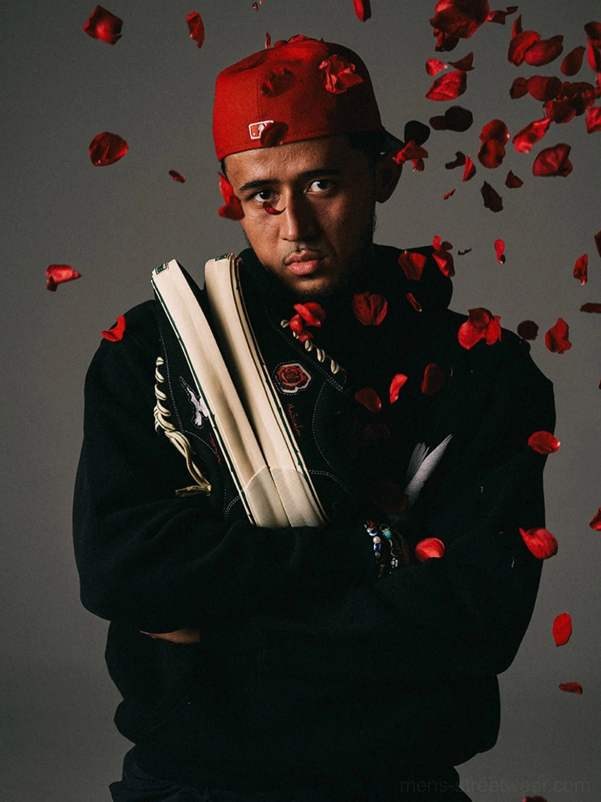 Creative streetwear portrait featuring black embroidered skate shoes, red bandana styling, and scattered rose petals