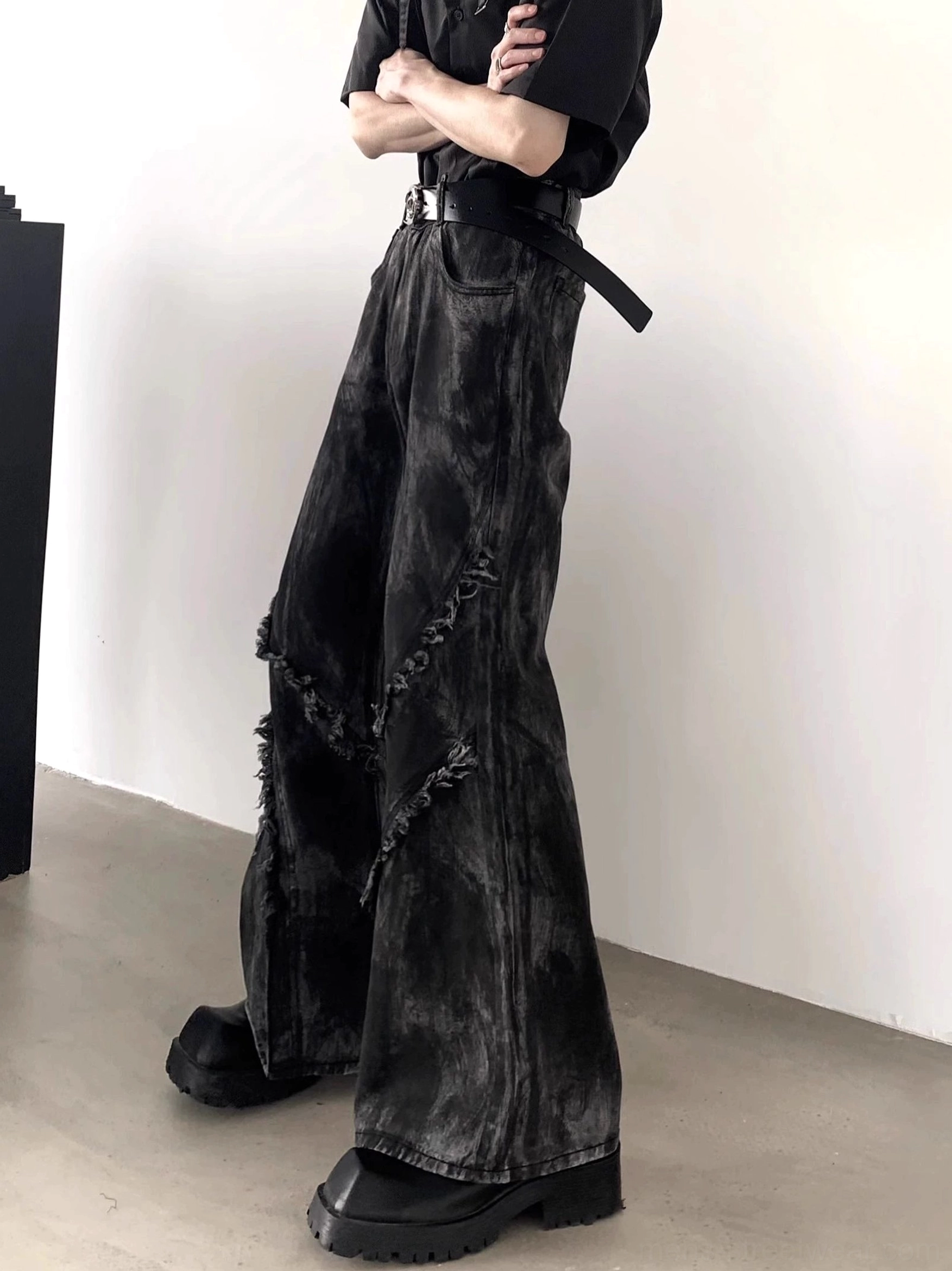 Side view of black faded denim flared jeans showing the dramatic wide-leg silhouette, distressed side seams, and vintage Korean streetwear aesthetic