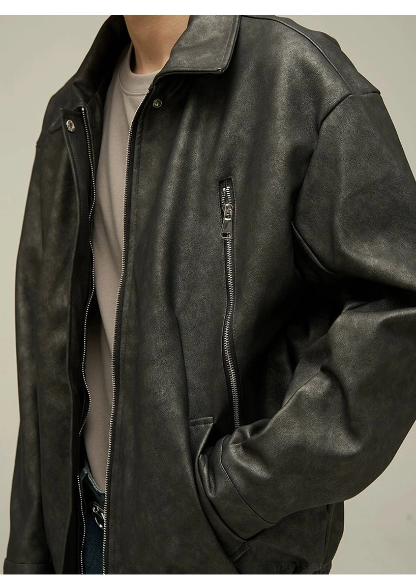 Close-up detail of black faded faux leather texture with spread collar, button closure, visible side zipper pocket, and beige layered tee