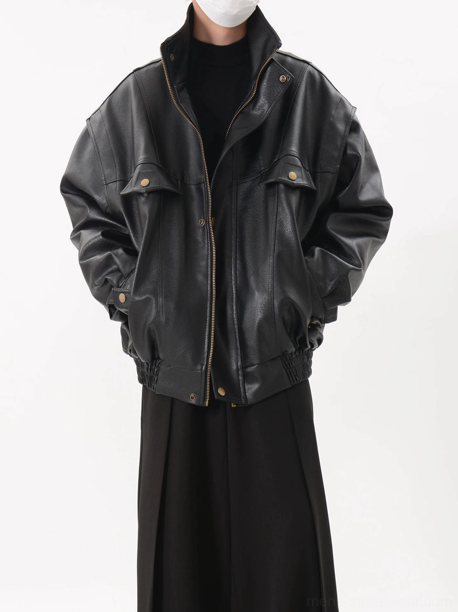 Close-up front view of black faux leather bomber jacket showing front zipper, flap chest pockets, snap hardware, high collar, smooth matte texture, and elasticated hem