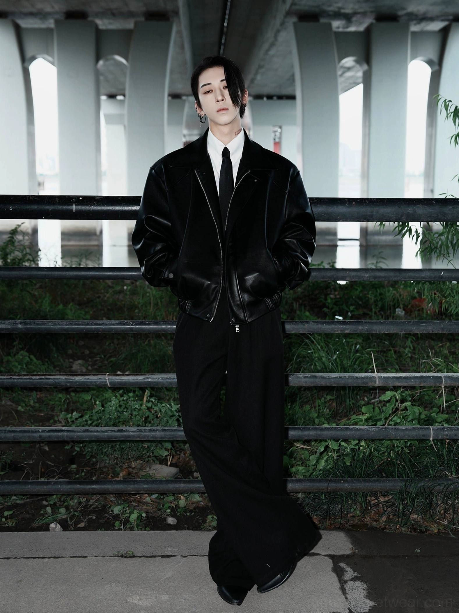 Side view of black faux leather bomber jacket with wide leg pants in dark minimalist streetwear outfit