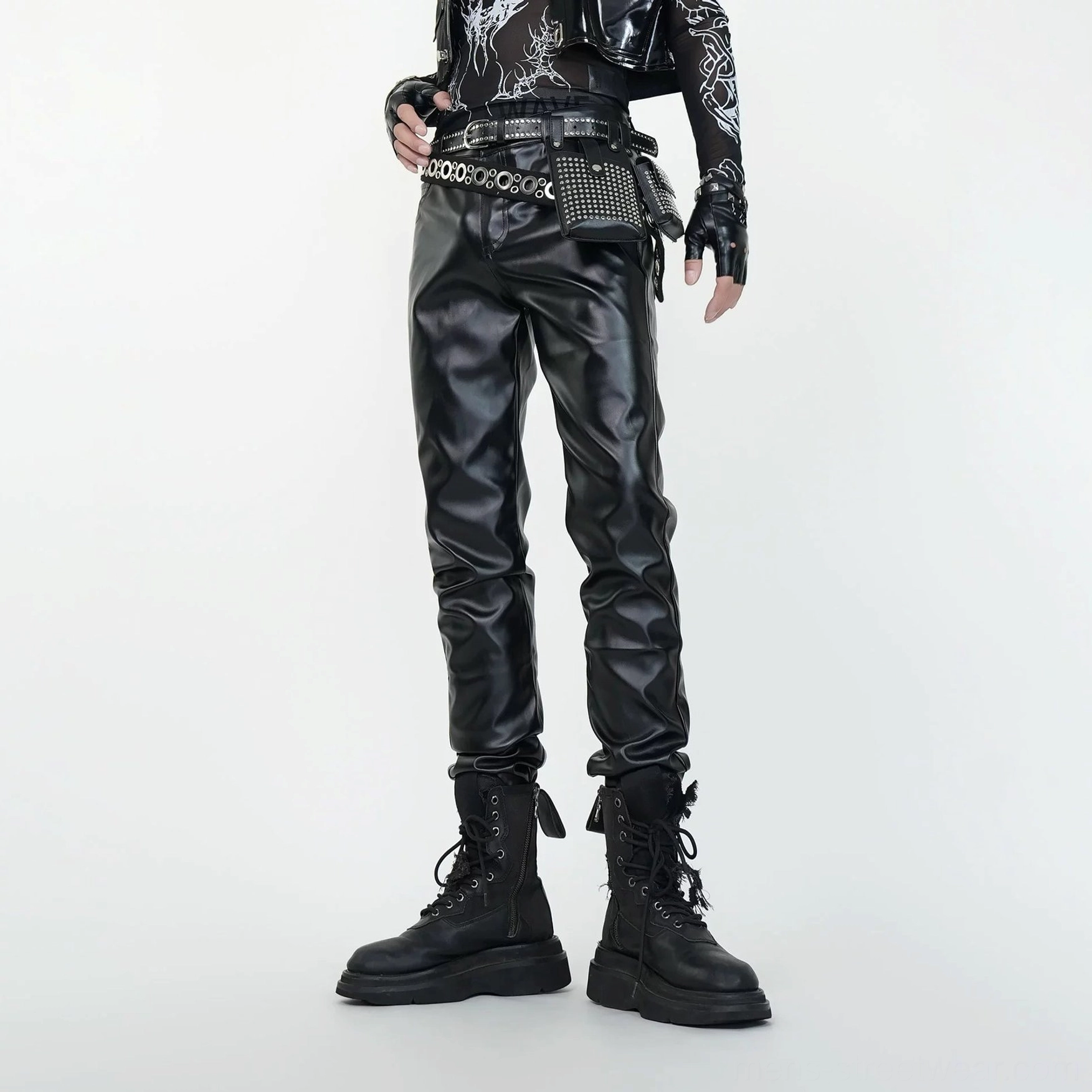 Three-quarter front view of black faux leather combat pants with fitted leg cut and goth punk streetwear styling
