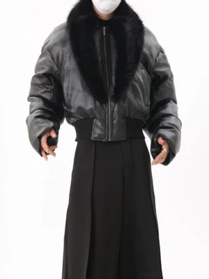 Front full-body view of a black faux leather cropped puffer jacket with oversized faux fur collar, padded sleeves, ribbed waistband, and front zipper styled with black wide-leg trousers