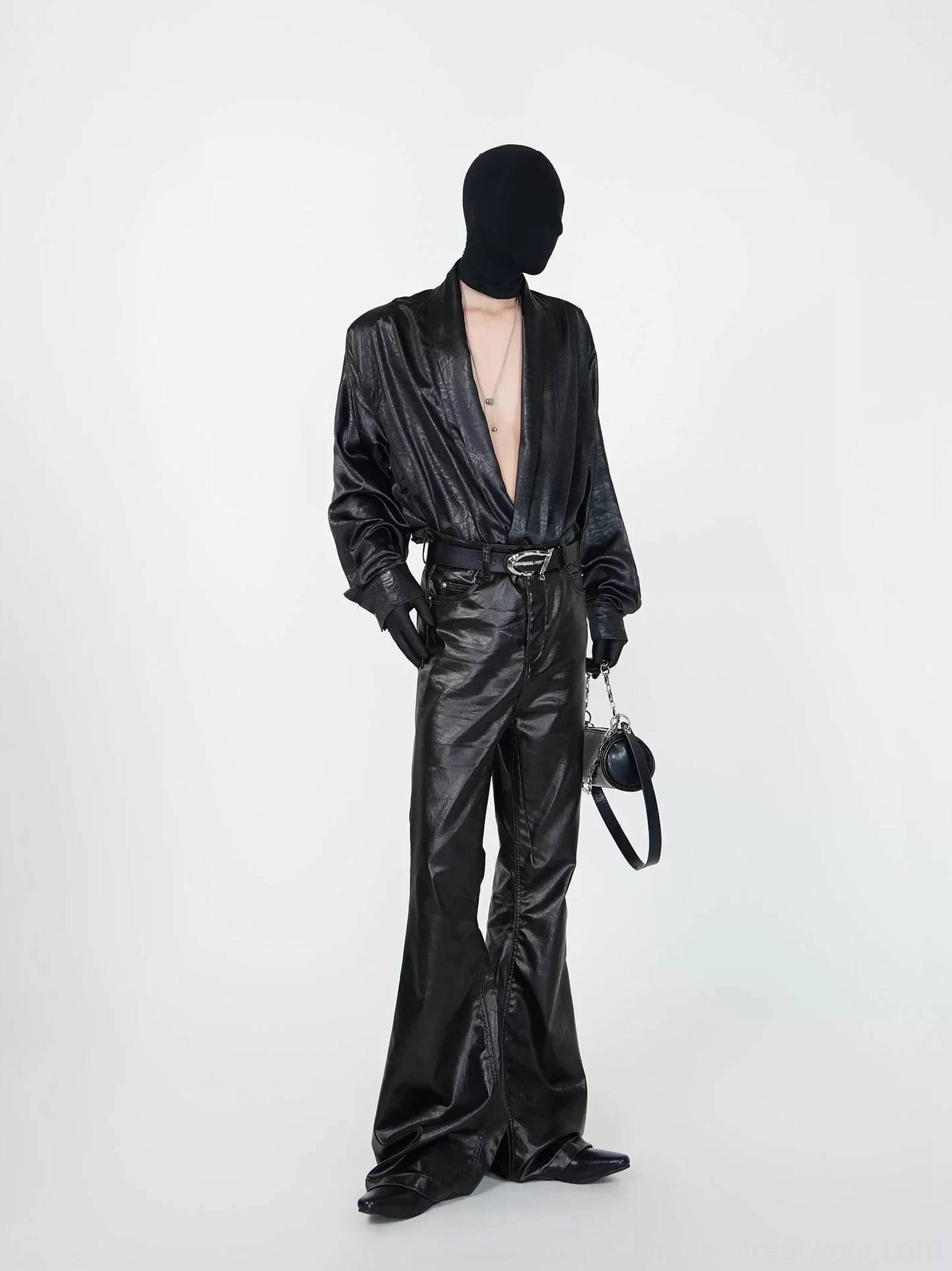 Side three-quarter view of black faux leather draped shirt with deep V neckline layered necklaces gloves and dark streetwear styling