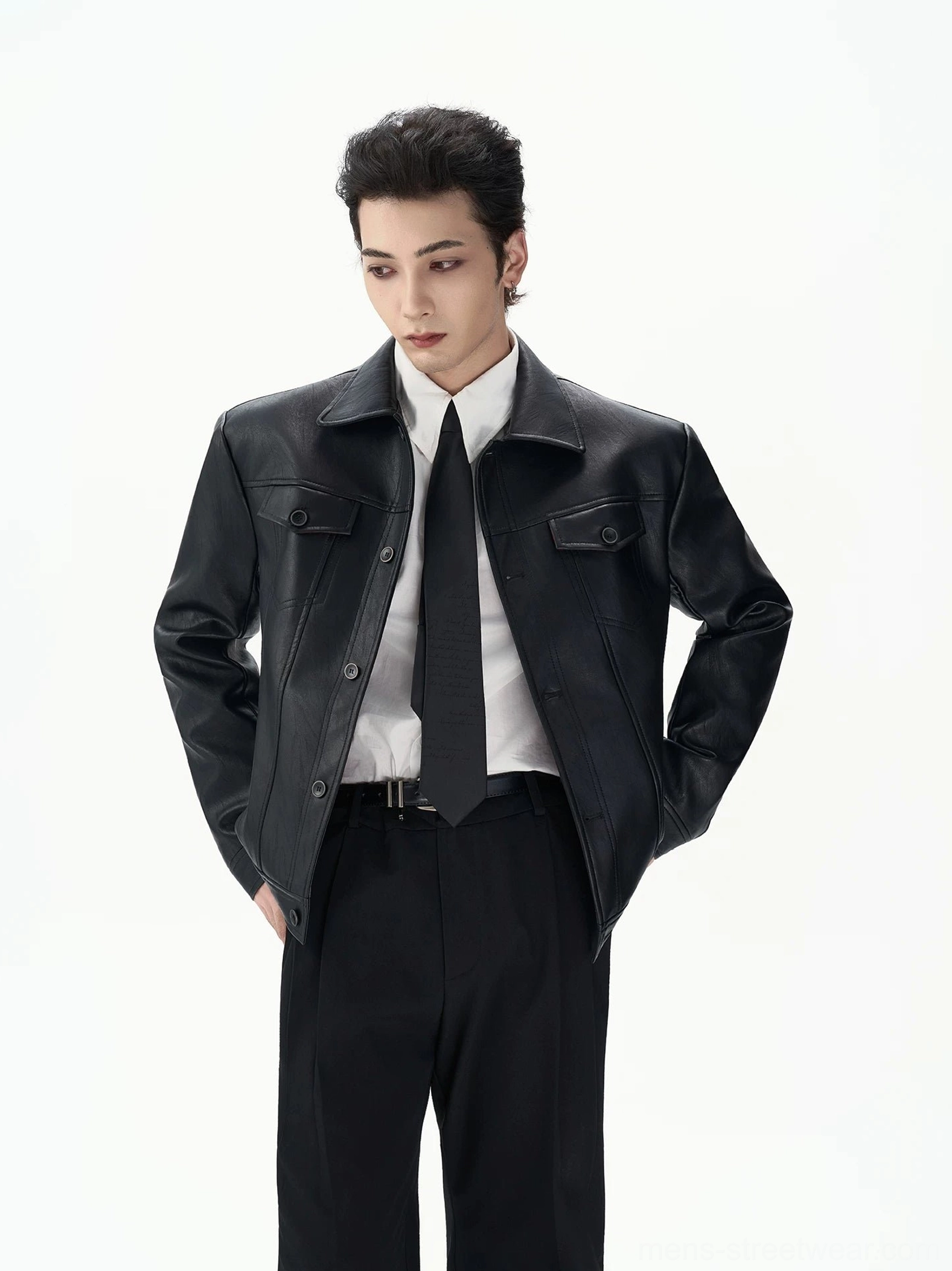 Close-up of black faux leather jacket showing button front closure chest flap pockets pointed collar and subtle textured grain