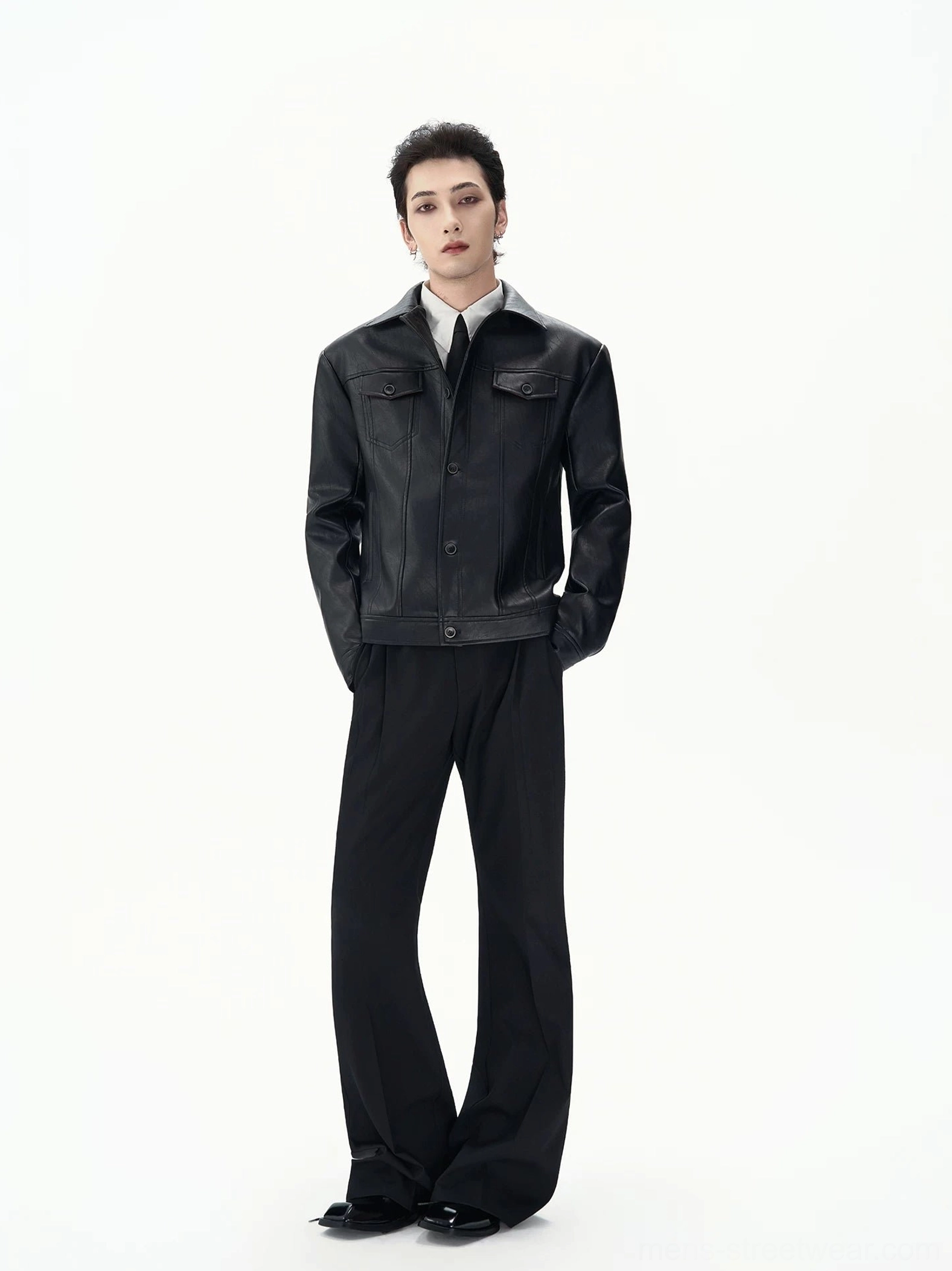 Male model wearing a black faux leather jacket with a clean tailored silhouette over formal black and white clothing