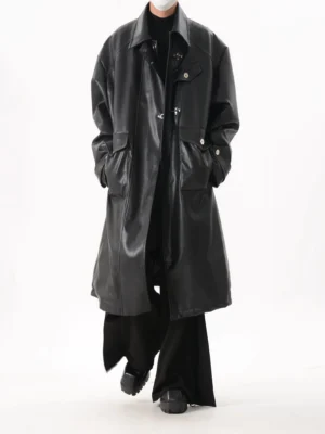 Three-quarter view of a loose-fit black faux leather long coat with hidden front placket, deep side pockets, and relaxed Korean streetwear silhouette