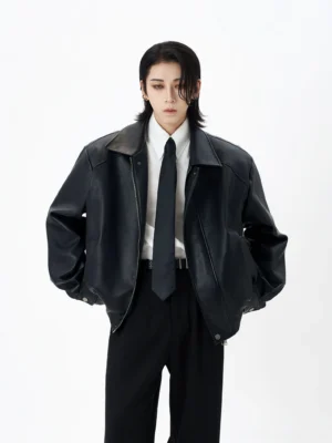 Black faux leather notched collar bomber jacket styled with white shirt and tie in studio