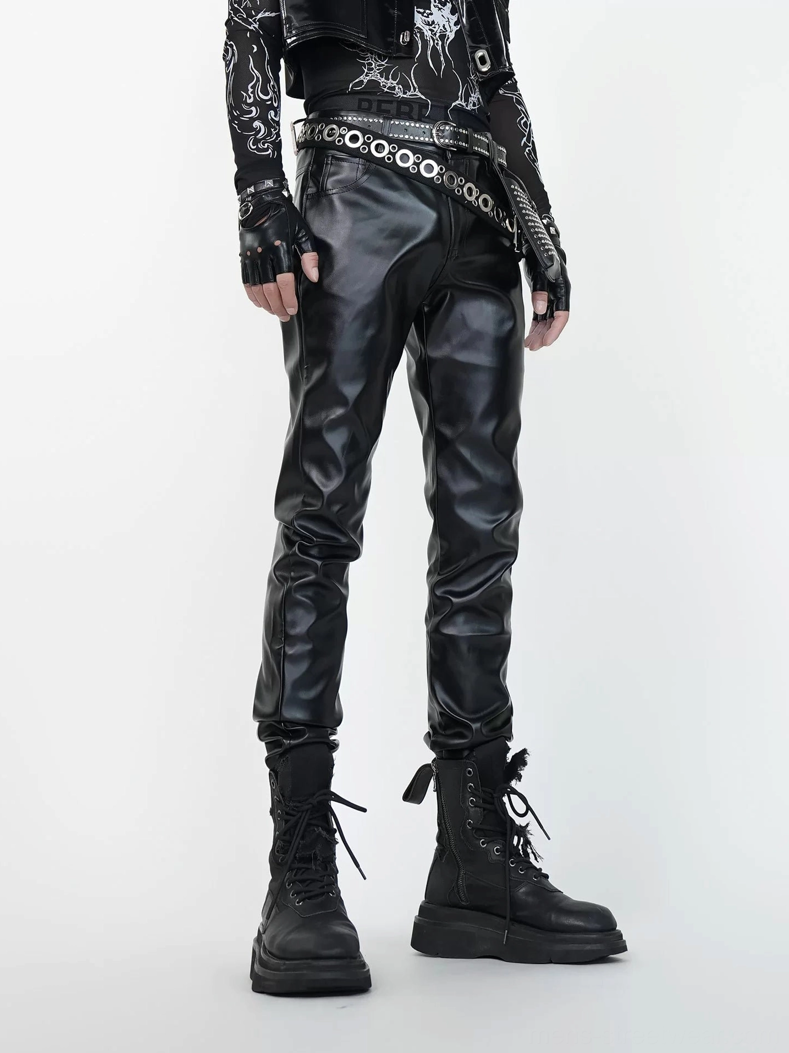 Front view of black slim faux leather combat pants styled with studded belts in a goth biker streetwear outfit
