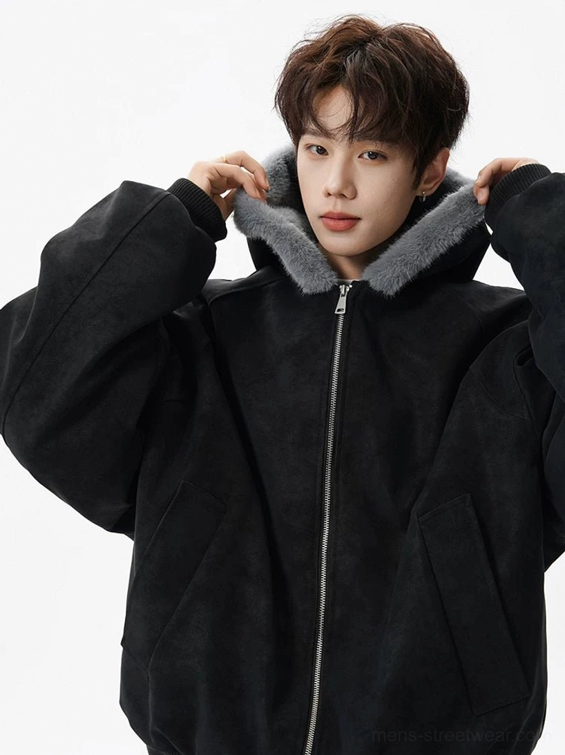 Close-up of black faux suede hooded bomber jacket showing soft gray plush hood lining, silver zipper, and relaxed streetwear construction