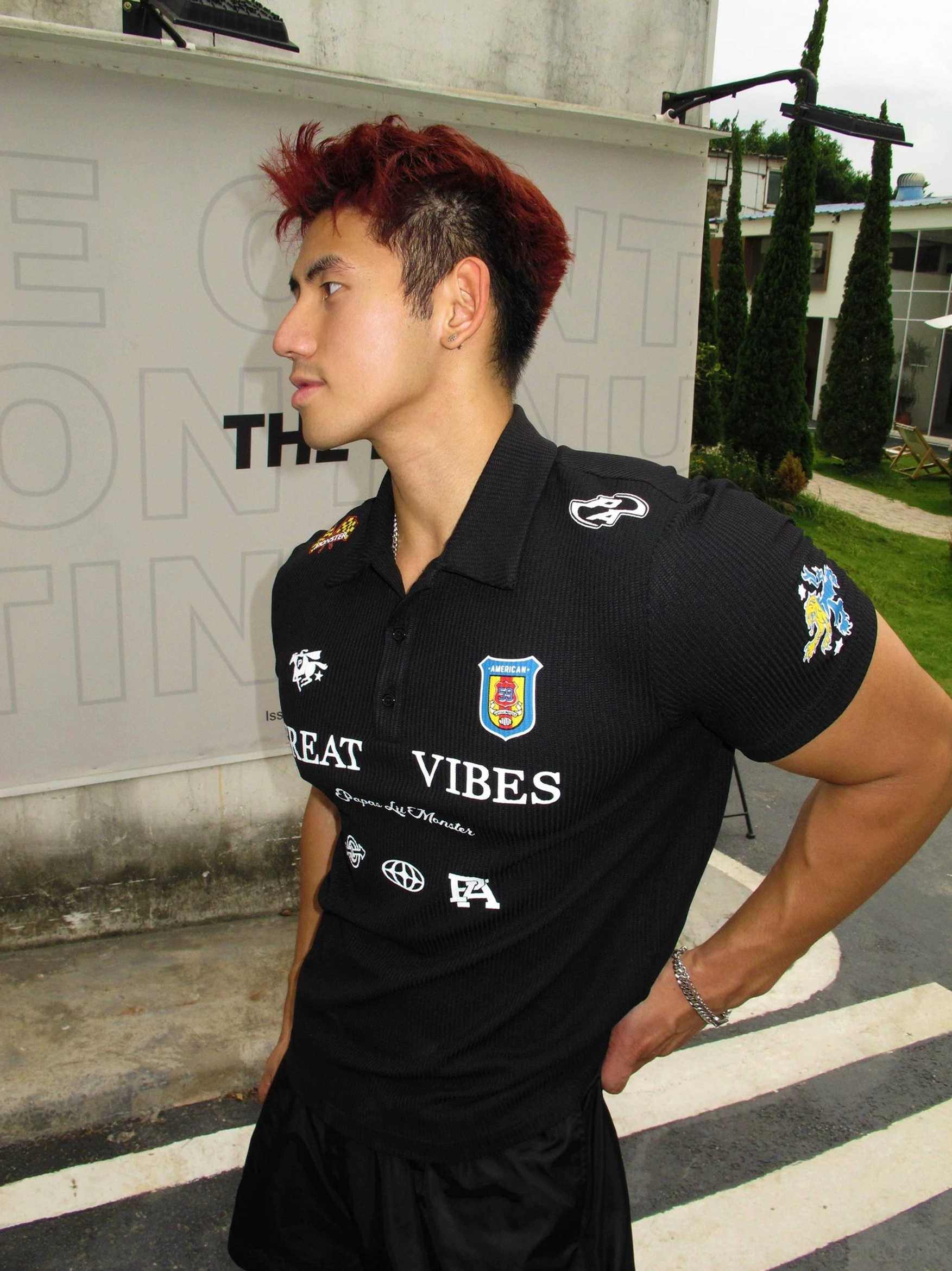 Side view of a fitted black Great Vibes graphic polo shirt styled with matching shorts for a relaxed Korean streetwear look