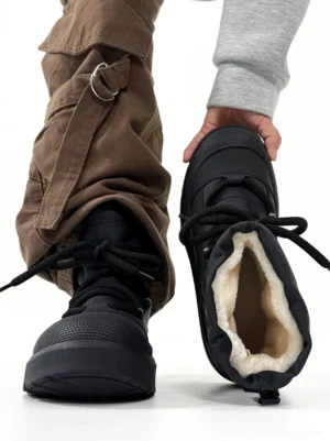 Black fleece-lined chunky winter streetwear boots worn with brown cargo pants, showing the plush inner lining, thick platform sole, and adjustable drawstring collar