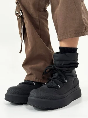 Side view of black fleece-lined chunky winter streetwear boots with padded ankle collar, rounded rubber toe cap, matte upper, and lace-up front