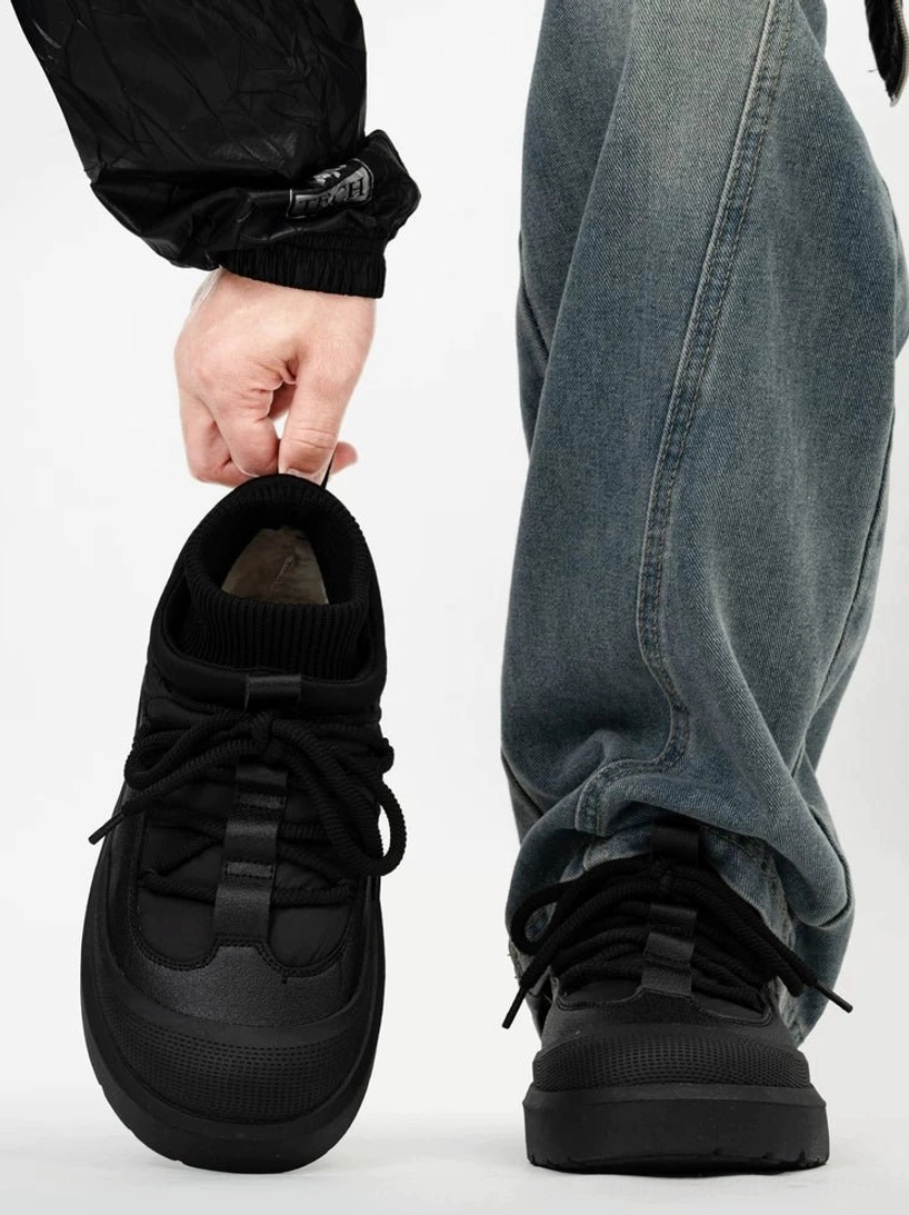 Black fleece lined lace-up winter sneakers held beside a worn shoe, showing the padded upper, warm inner lining, round toe cap, and treaded rubber sole