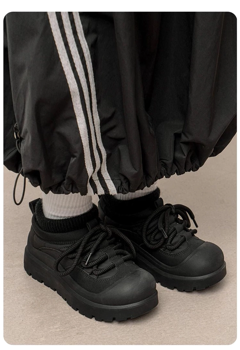 Black fleece-lined platform sneakers shown from a low ground angle with full lacing, visible fleece lining, chunky sole, and lugged tread