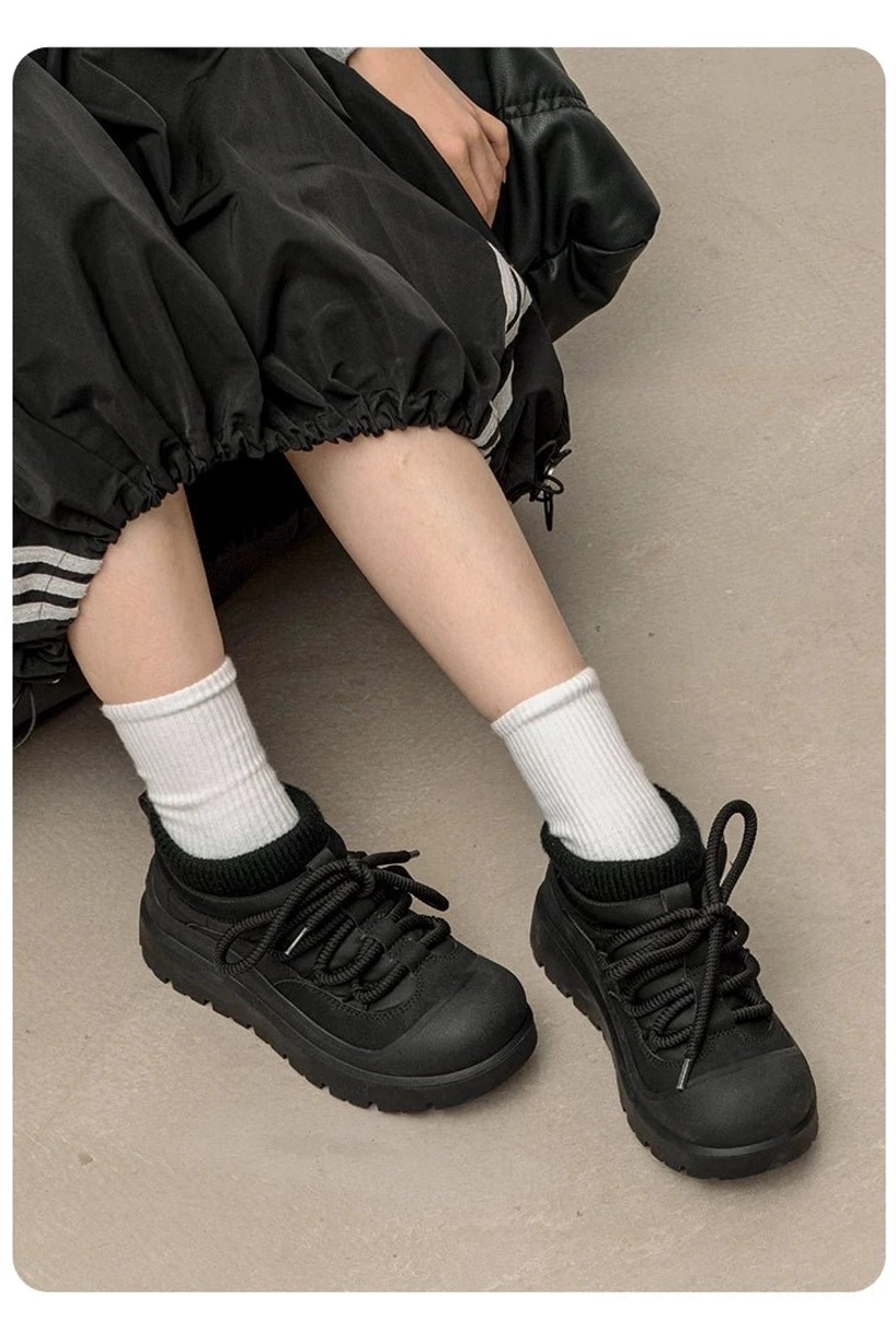 Black fleece-lined platform sneakers worn with relaxed track pants and white socks showing the low-top silhouette and soft collar
