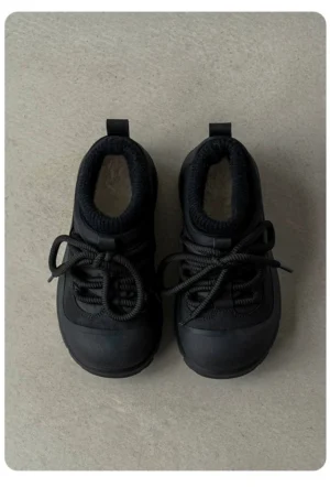 Black fleece-lined platform sneakers shown from a top-down view with chunky rubber outsole, lace-up front, ribbed collar, and winter streetwear design