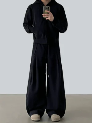 Black floor-grazing wide-leg lounge pants styled with an oversized zip-up hoodie in a minimalist streetwear studio mirror selfie