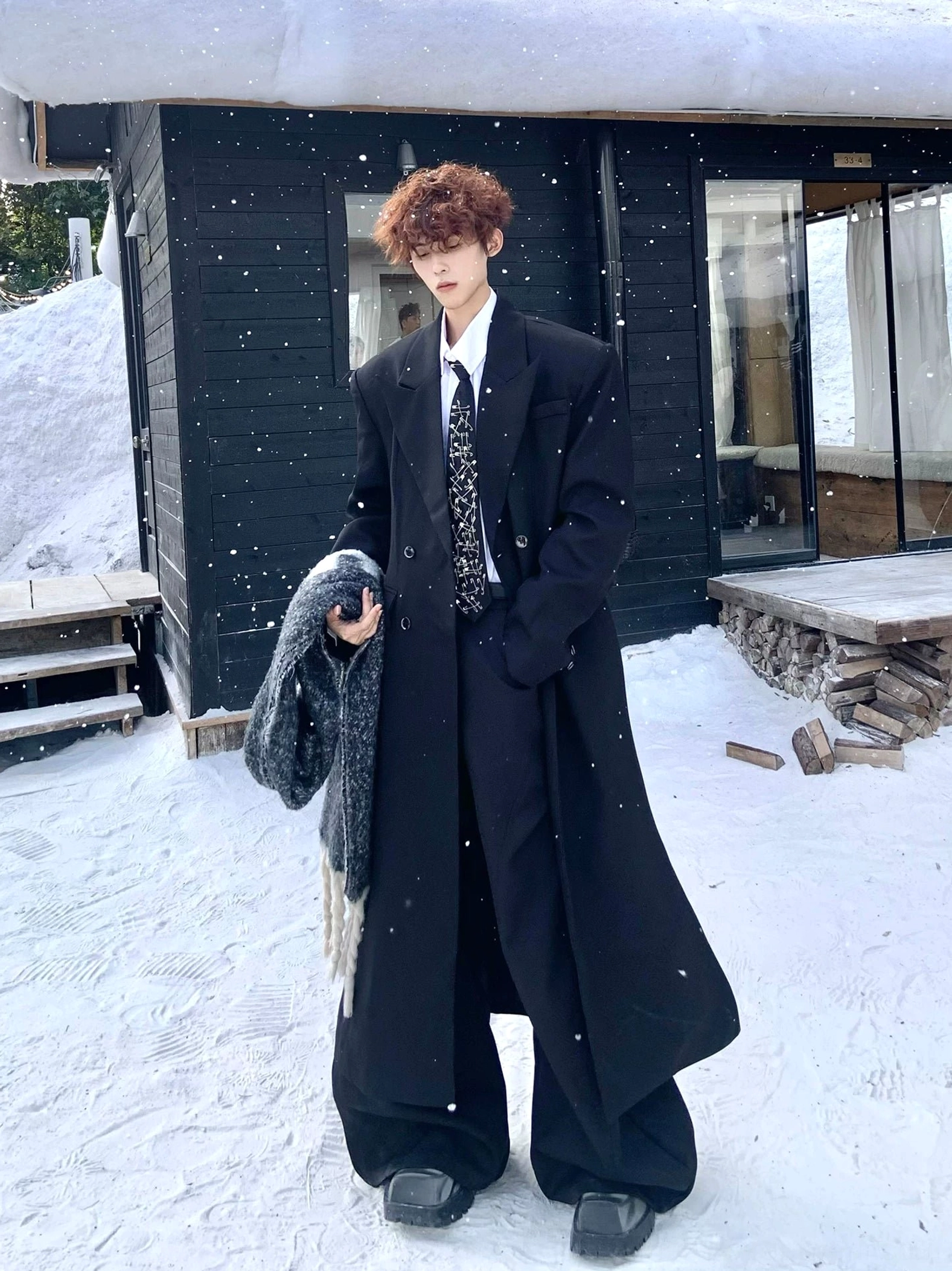 Black floor-length oversized overcoat with peak lapels styled with wide-leg trousers and platform shoes