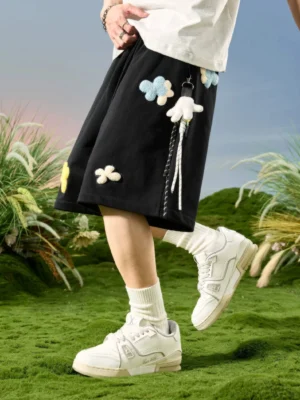 Black floral appliqué relaxed streetwear sweat shorts side back view with contrast stripe trim and hanging charms