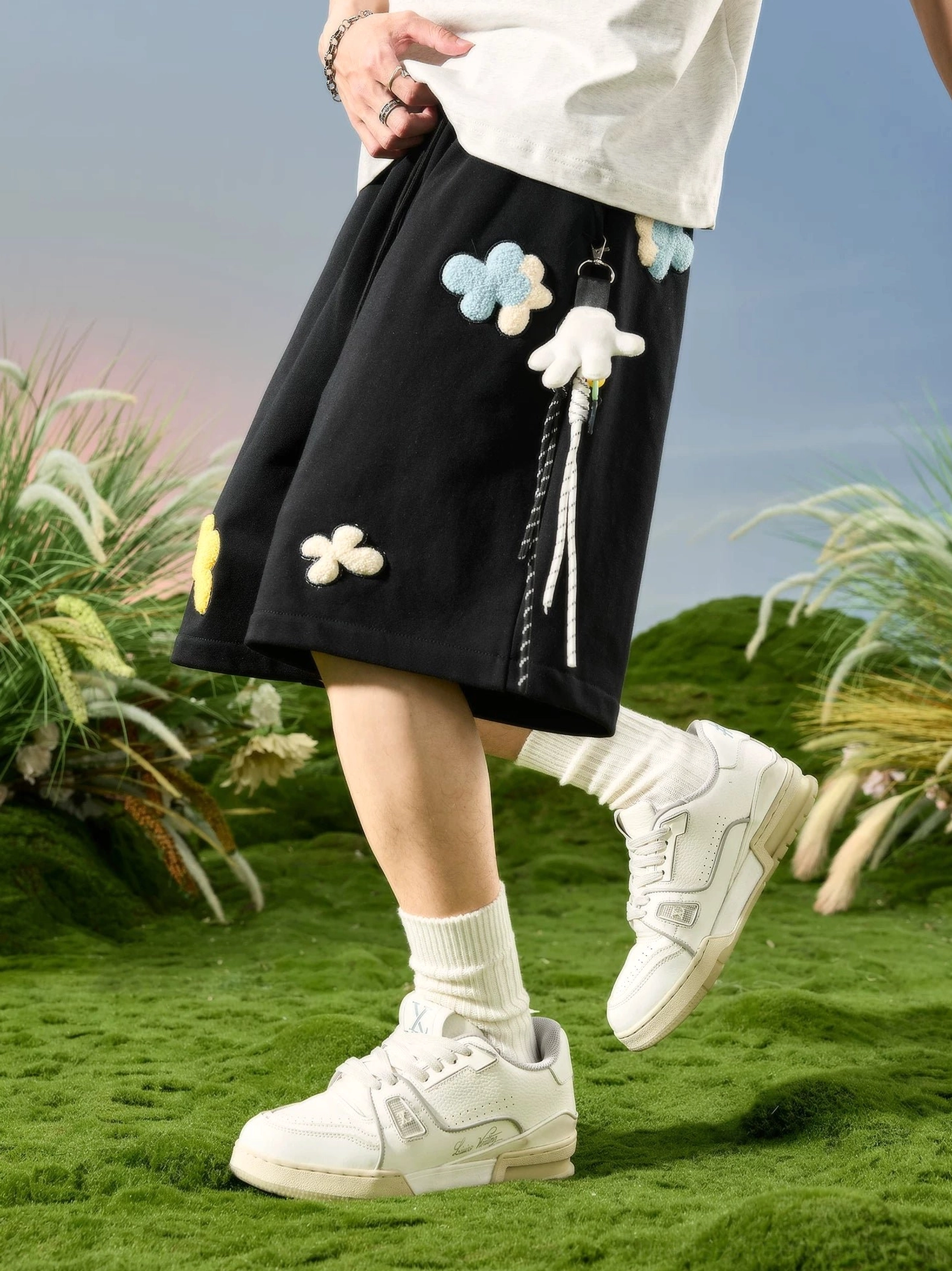 Black floral appliqué relaxed streetwear sweat shorts side back view with contrast stripe trim and hanging charms