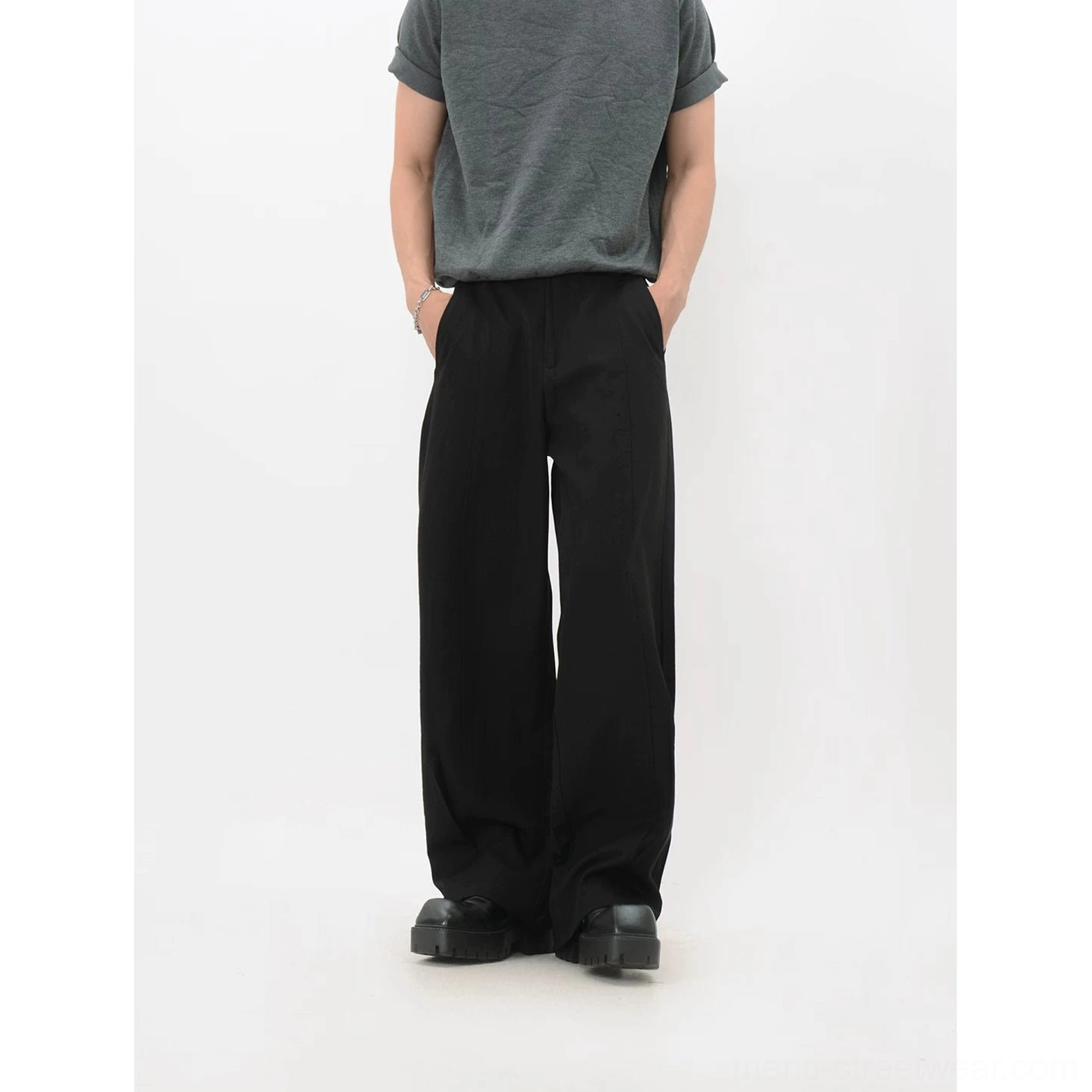 Black fluid wide-leg trousers shown from the front with deep side pockets, clean tailored lines, and a modern oversized silhouette