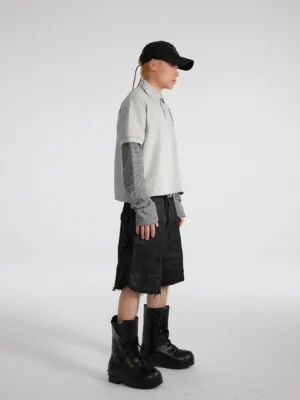 Male model wearing washed black frayed-hem cargo denim shorts in a relaxed wide-leg streetwear outfit shown from the right side