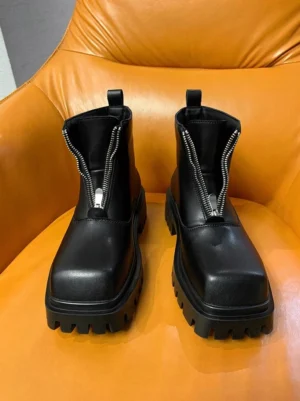 Black front-zip platform boots partially unzipped on an orange leather chair, revealing the microfiber-lined interior and matte finish