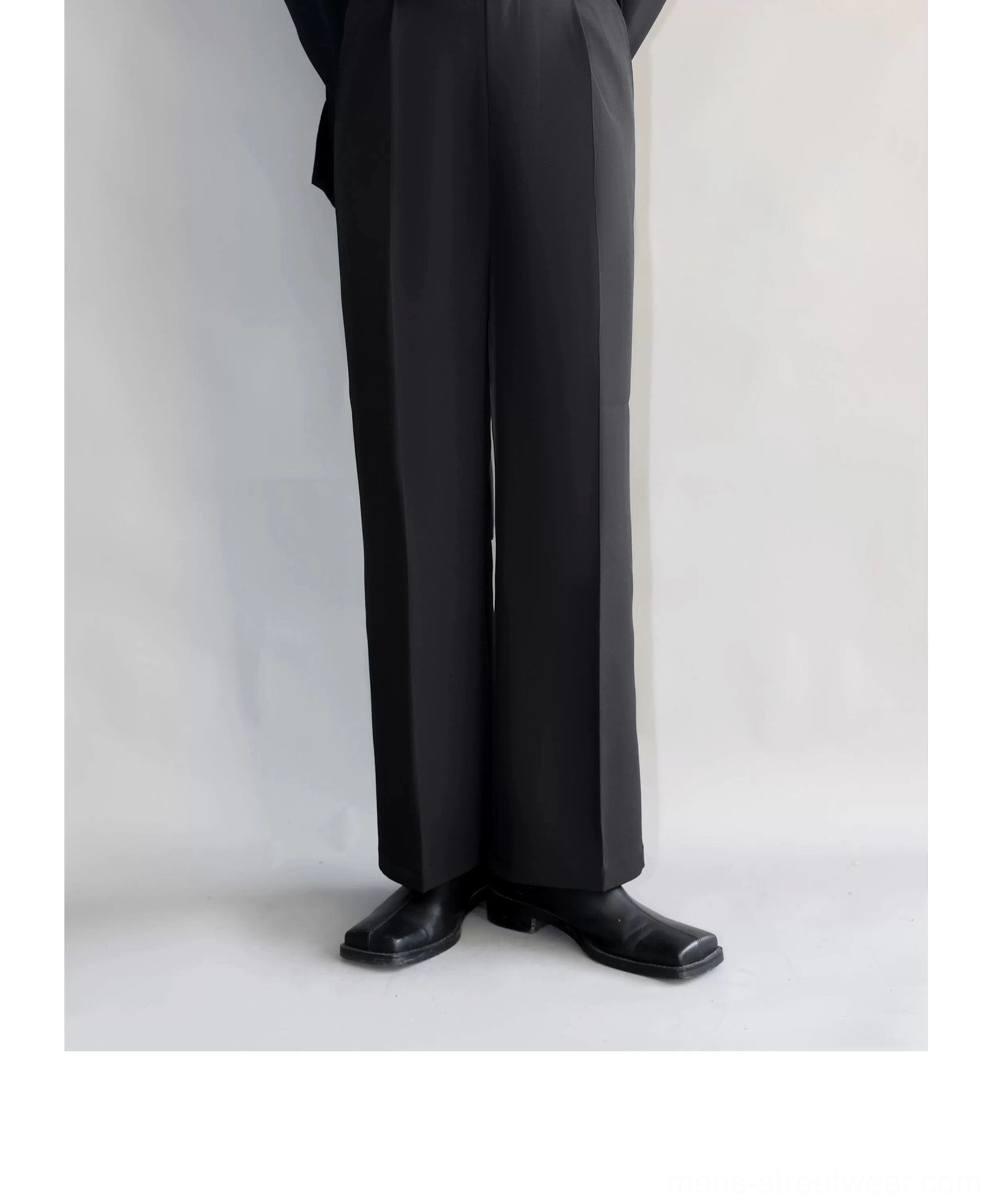 Close low-angle view of black full-length straight-leg suit trousers with matte fabric and black leather shoes